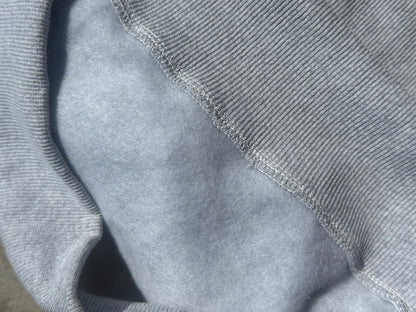 Close-up of a light gray ribbed knit fabric meeting a smoother light gray fleece or microfiber lining, showing the texture and stitching detail of the offered mock neck sweatshirt.